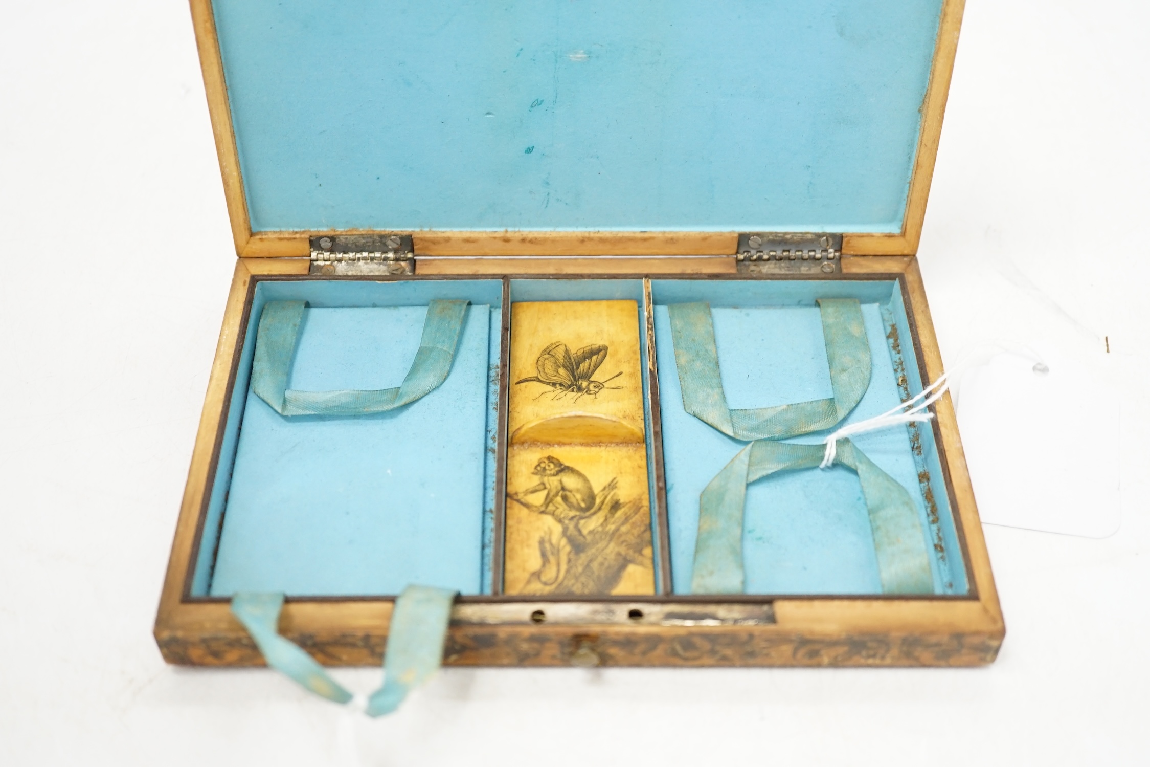 An early 19th century penwork box with country scene decoration to top cover and monkey and butterfly decoration to interior sectional cover, 17cm wide. Condition - box cover worn, interior of box fair